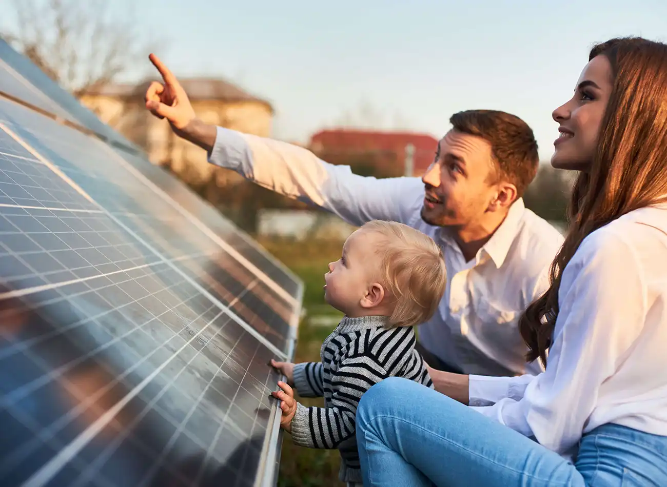Parents and young sun standing by a solar panel looking upwards.