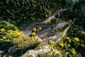 Neamt chargers Aeral drone view of winding road from high mountain pass.